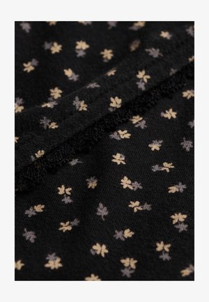 Tela negra con pequeños patrones de tréboles de cuatro hojas en beige y gris y una costura texturizada que atraviesa en diagonal.