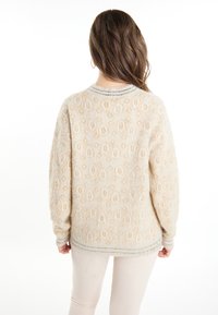 Maglione color crema con texture, finitura morbida e pelosa e un motivo sottile. Presenta un colletto e dei polsini a coste con un accentuazione grigia.
