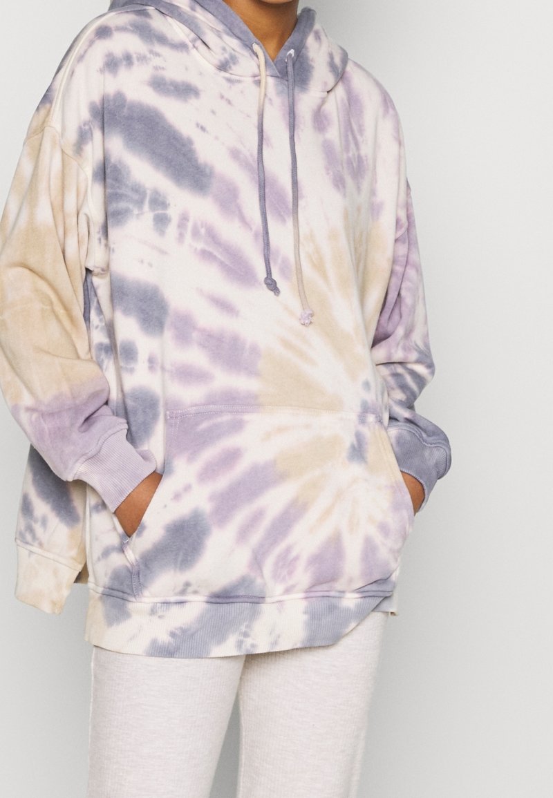 Felpa con cappuccio tie-dye che presenta tonalità pastello di viola, beige e crema, con cappuccio regolabile, maniche lunghe e tasca frontale.