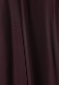 Burgundi színű szövet, sima, matt textúrával, lágyan hullámzik, finom fényességet és puha vonalakat mutat. Különböző textil alkalmazásokhoz megfelelő.
