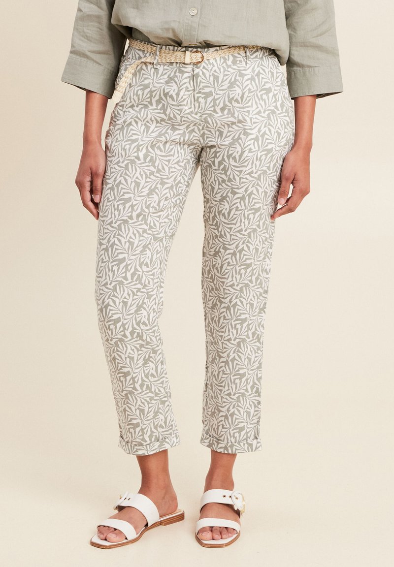 Lichte, gemusterde broek in zacht groen en wit, met een botanisch ontwerp. Gecombineerd met witte sandalen. Versierd met een gevlochten riem.