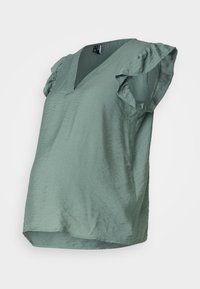 Schwangerenbluse aus strukturiertem, weichem grünem Stoff. Mit V-Ausschnitt und kurzen Rüschenärmeln. Lockerer Schnitt mit leicht abgerundetem Saum.