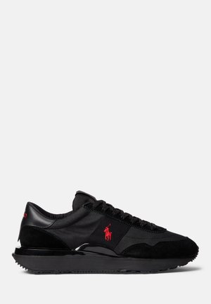 Sneaker sportive nere realizzati con una combinazione di materiali scamosciati e tessili. Accento distintivo del logo rosso e suola in gomma texture.