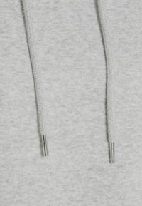 Material de pulover gri cu o textură moale, având două șnururi cu agrafe metalice argintii. Vedere detaliată a suprafeței materialului.
