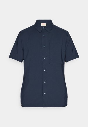Košulja kratkih rukava u tamnoplavoj boji, napravljena od tkanine, sa prednjim džepom, kopčanjem na dugmad i klasičnim dizajnom ovratnika.