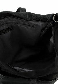 Zwart leren tas interieur met een gladde voering, een enkele ritszak en zachte textuur randen, zonder zichtbare externe hardwar.
