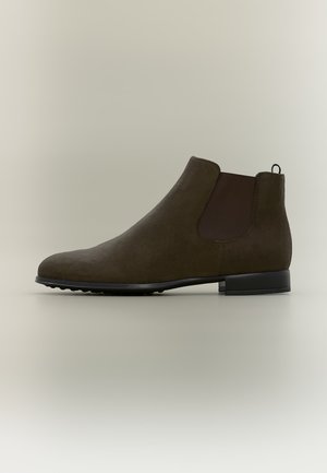 Chelsea boot alla caviglia in suede marrone con pannello elastico laterale e tacco basso nero su sfondo neutro.