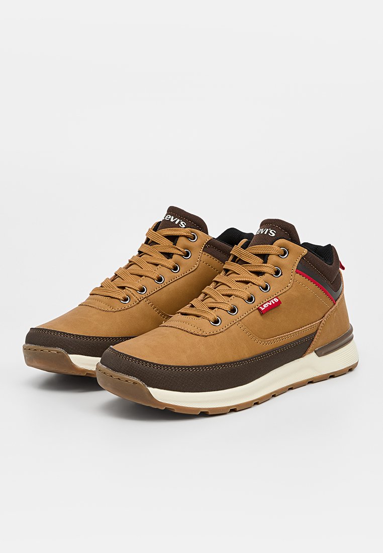 Sneaker in suede e tessuto marrone con suola in gomma, presentano accenti in marrone chiaro e scuro, lacci e un piccolo dettaglio del logo rosso.