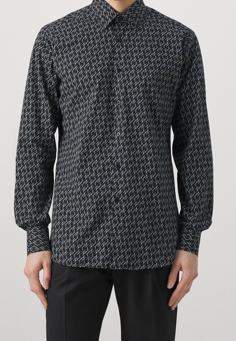 Camicia a maniche lunghe in tessuto nero con un motivo bianco ripetitivo. Presenta un colletto a camicia e polsini, con un design slim fit.
