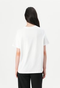 White cotton t-shirt with a classic crew neckline and short sleeves, featuring a relaxed fit and smooth texture. Simple, clean design.