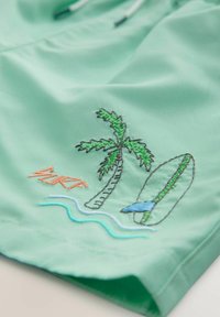 Shorts de bain verts ornés de palmiers brodés, d'une planche de surf et de vagues. Comprend des accents orange et bleu, fabriqués en matériau léger.