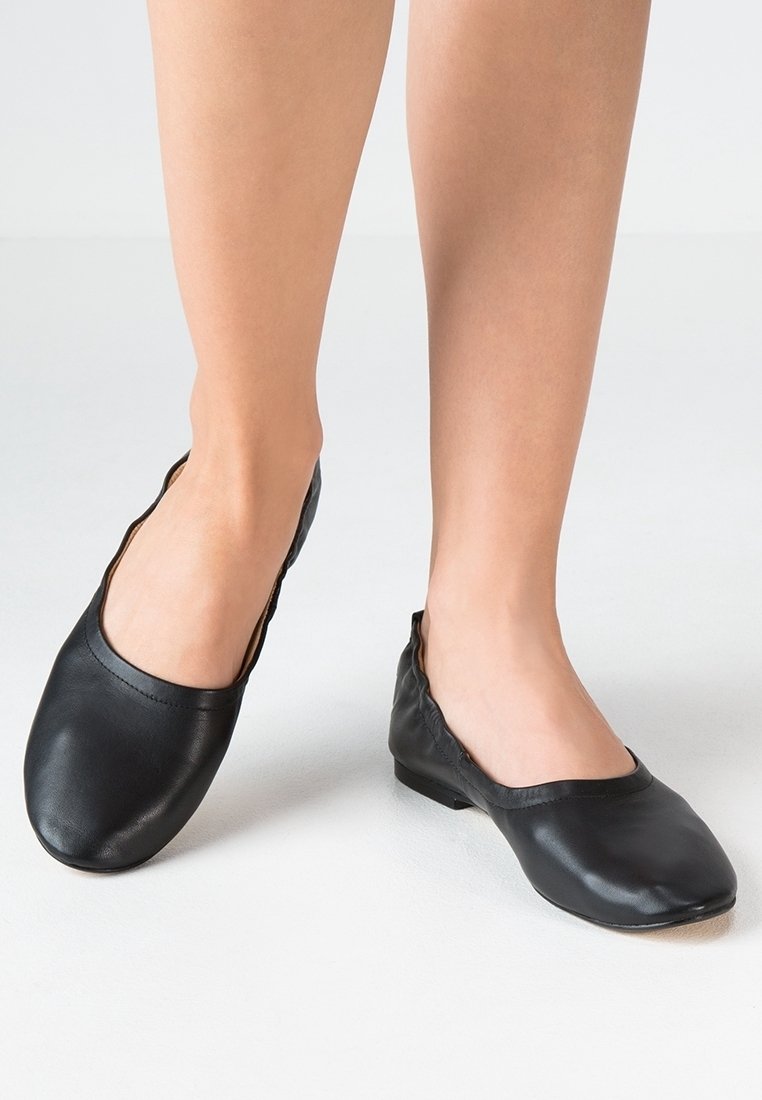 Ballerines en cuir noir avec un design épuré, un bout arrondi et des bords élastiqués pour un maintien sûr. Texture lisse, style minimaliste.