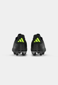 Schwarze Fußballschuhe mit strukturiertem Material, aerodynamischer Form und leuchtend grünen Akzenten sowie einem Drei-Streifen-Logo an der Ferse.