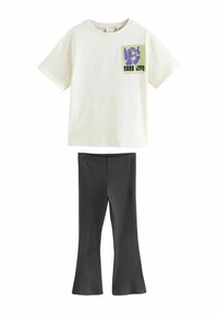 T-shirt en coton crème avec un graphique floral carré en violet et vert, associé à un pantalon évasé gris foncé en tissu doux et extensible.