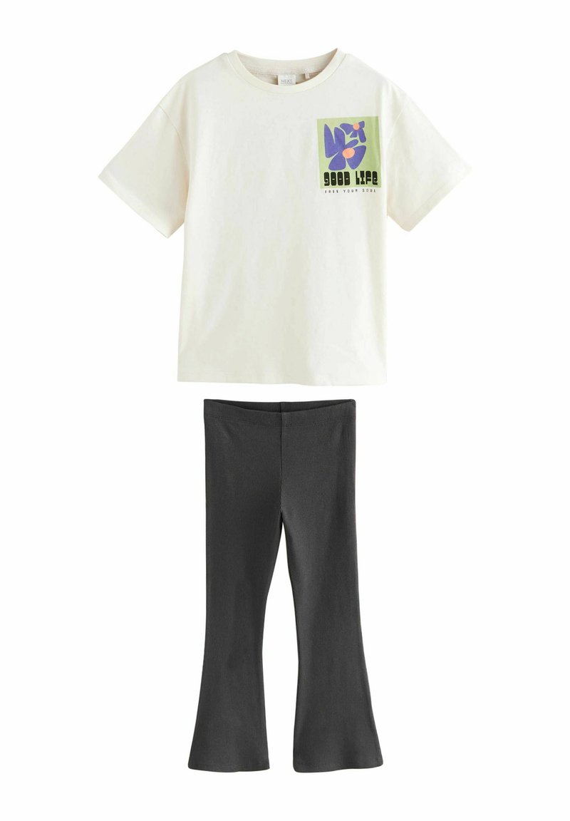 T-shirt en coton crème avec un graphique floral carré en violet et vert, associé à un pantalon évasé gris foncé en tissu doux et extensible.