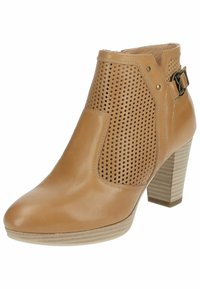 Bottine en cuir tan avec des perforations découpées, un talon carré, un détail de boucle sur le côté et une texture lisse. Dispose d'un design à bout rond.