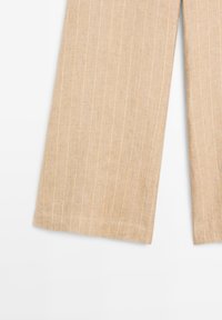 Pantaloni di lino beige con righe verticali bianche, caratterizzati da un design a gamba larga e tessuto strutturato. I bordi sono rifiniti con cura.