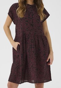 Robe à manches courtes avec un design à boutons sur le devant, présentant un motif floral bordeaux sur fond noir et des poches latérales.