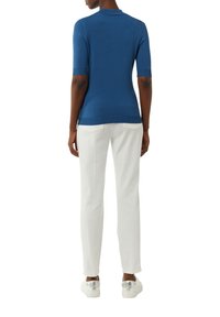 Niebieski, krótkie rękawy, dzianinowy top o dopasowanym kroju z okrągłym dekoltem, w połączeniu z białymi, dopasowanymi spodniami i sneakersami z przezroczystą podeszwą.