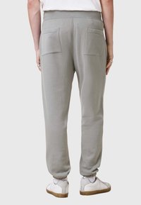 Ljust grå sweatpants med smalnade ben, elastisk midja och två bakfickor. Slät textur, avslutad med elastiska manschetter vid anklarna.