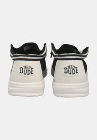 Scarpe casual in bianco e nero con tomaia in tela morbida, linguetta posteriore rimovibile e patch logo "HEY DUDE" sul tallone, dotate di suola testurizzata.