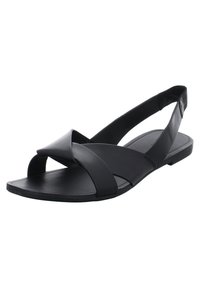 Musta litteä sandaali, jossa on ristikkäiset nahkaremmit varpaiden päällä ja joustava kantaremmi heelin ympärillä.