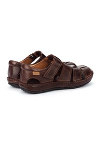 Braune Leder-Sandalen mit geflochtenen Riemen, einem geschlossenen Fersenbereich und einer Detailnaht. Texturiertes Fußbett und Gummisohle für guten Halt.