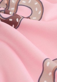 Tessuto di cotone con uno sfondo rosa e un motivo di ciambelle marroni, decorate con sprinkles bianchi; texture liscia con una leggera lucentezza.