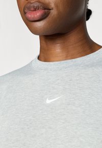 Ανοιχτό γκρι βαμβακερό φούτερ με ριμπ τελείωμα στον λαιμό και μικρό λευκό λογότυπο Nike μπροστά. Λείο υλικό και casual εφαρμογή.