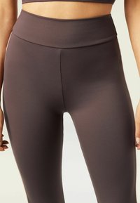 High-waisted, fitted leggings in a deep brown color. Made from smooth, stretch fabric with no visible seams or patterns.