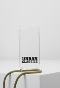 Gjennomsiktig telefondeksel med svart "URBAN CLASSICS"-tekst nederst, utstyrt med et teksturert olivengrønt bånd for bæring.
