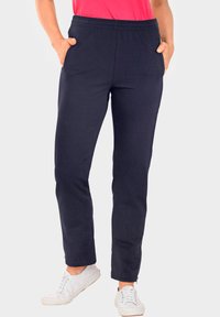 Marineblauwe sweatpants met een elastische tailleband, zijzakken, taps toelopende benen en een zachte, gladde textuur, gedragen met witte sneakers.
