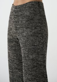 Schwarz-graue gerippte Strickhose mit hohem Bund, geradem Bein und weicher Textur mit subtilen Farbvariationen.