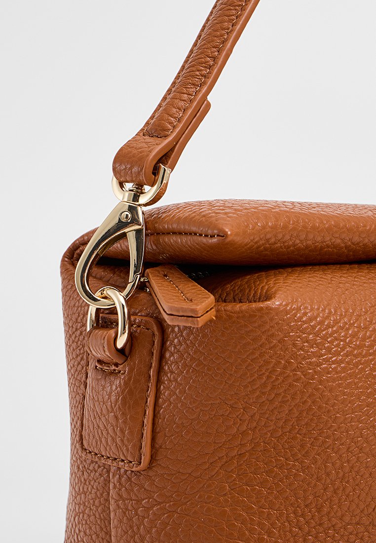 Sac à main en cuir marron avec une finition texturée, présentant un fermoir en métal doré et une bandoulière réglable. Comprend un détail de poche latérale.