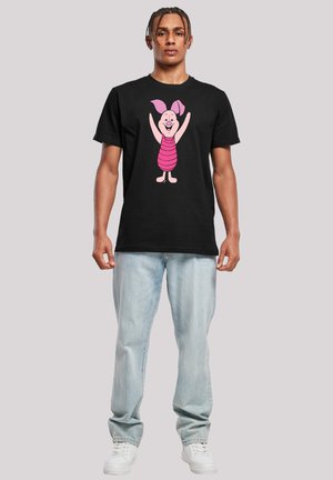 Svart bomull t-skjorte med en grafikk av en rosa tegneseriegris med armene hevet. Designet inkluderer horisontale striper på grisens kropp.