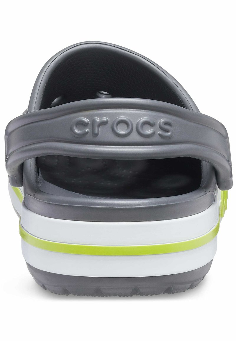 Grijze plastic Crocs met een dikke witte zool en een gele accentstreep. Beschikt over een rond ventilatieontwerp en een achterband voor een veilige pasvorm.