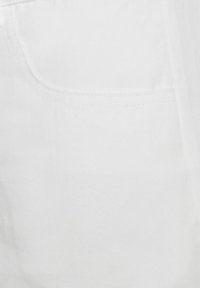 Tessuto di denim bianco con una texture sottile, dotato di una tasca posteriore e dettagli di cucitura puliti.