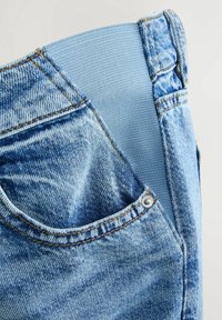Světle modré džíny z denimu se strečovým, měkkým pasem. Tkanina má opranou texturu, obsahuje stříbrný knoflík a boční kapsu.