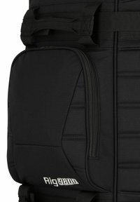 Mochila negra hecha de un tejido duradero, con un bolsillo frontal con cremallera, secciones acolchadas y correas ajustables. Nombre de la marca "Rig 9800" visible.