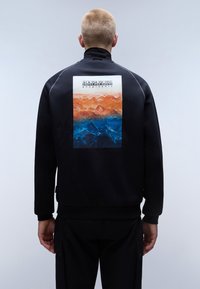 Felpa nera con collo alto, caratterizzata da una stampa di paesaggio montano arancione e blu sul retro. Tessuto morbido, vestibilità comoda.