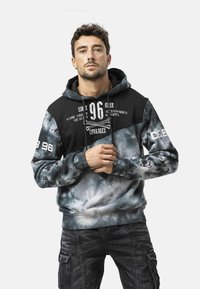 Zwarte en grijze capuchontrui met tie-dye patroon, grafische print en trekkoorden. Voorzien van een voorzak en geribbelde manchetten.