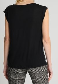 Black short-sleeved top with a round neckline, made from a soft fabric. Back features subtle stitching details and relaxed fit.
