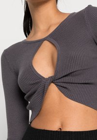 Šedý žebrovaný top s dlouhým rukávem, který má twist design s vykrojeným detailem na hrudi a zaobleným výstřihem.
