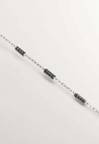 Pulsera de cadena de plata con acentos de piedras negras rectangulares, con un acabado suave y diseños de eslabones alternos para aportar textura y dimensión.