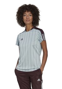 T-shirt de sport bleu clair avec des rayures verticales foncées, col rond, manches courtes et accents bordeaux foncé sur les épaules. Logo Adidas présent.
