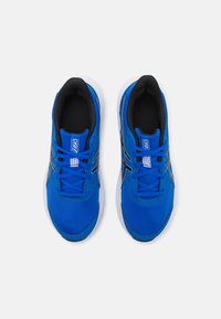 Baskets de sport bleues avec tige en mesh, fermeture à lacets, accents noirs et semelle blanche. Matériau texturé et détail du logo sur la languette.