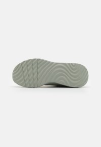 Semelle de chaussure en caoutchouc verte avec motif ondulé et rainures horizontales. Embout arrondi et surface texturée pour une meilleure adhérence. Design épuré.