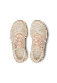 Beige Laufschuhe mit einem Mesh-Obermaterial, rosa Schnürsenkeln und einer leicht gepolsterten Sohle. Mit einem weißen Logo und strukturierten Details an den Seiten.