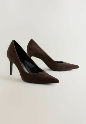 Pantofi cu toc înalt din suede maro, cu vârful ascuțit și o siluetă elegantă. Încălțămintea are un interior lucios de culoare neagră și un toc subțire, de tip stiletto.