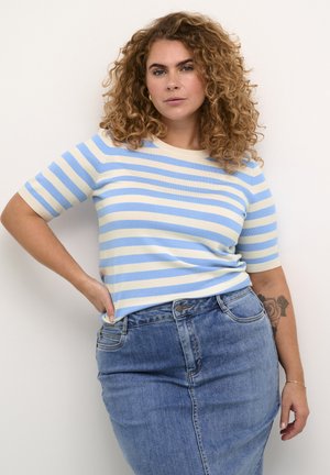 Gestreepte gebreide top in lichtblauw en crème, korte mouwen, ronde halslijn. Gecombineerd met een high-waisted spijkerrok, met een tattoo op de arm zichtbaar.